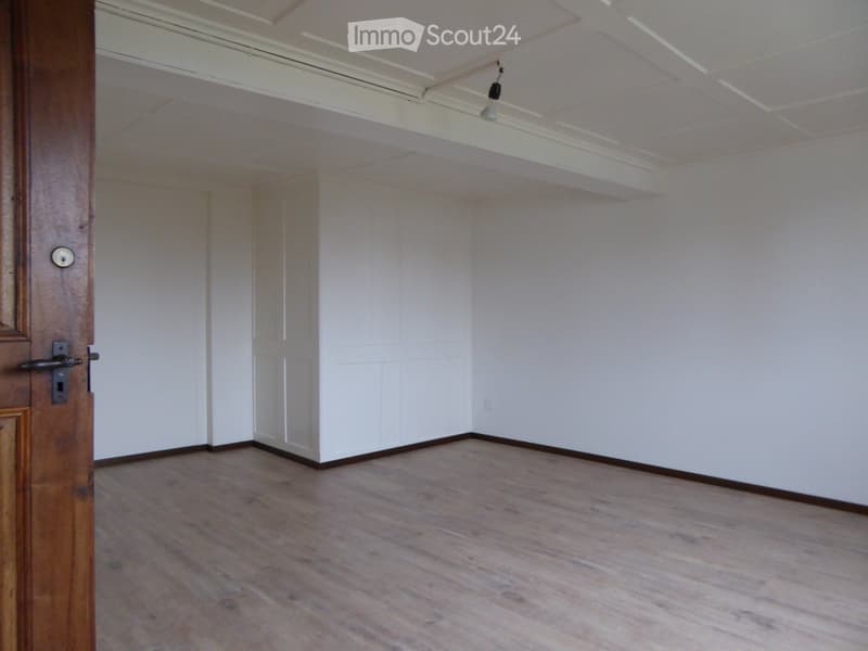 Empty room with wooden flooring, white walls, and a wooden door frame visible. No furniture or equipment present.
