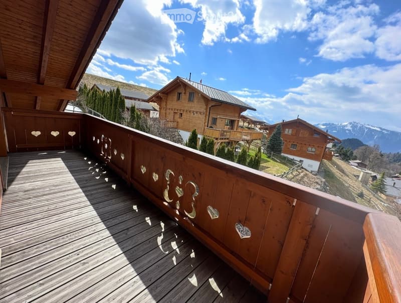 wooden deck, wooden railing with heart designs, view of mountains and houses