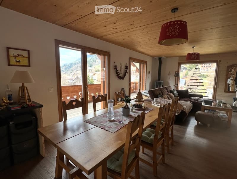 Dining room with wooden table, chairs, couch, lamp, and a view of the mountains