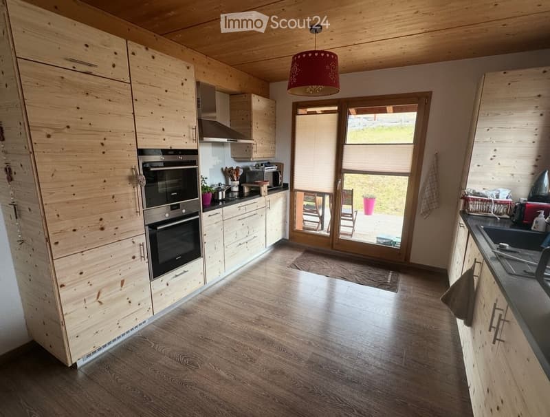 modern kitchen with wooden cabinets, wooden floor, large windows, view of the outside