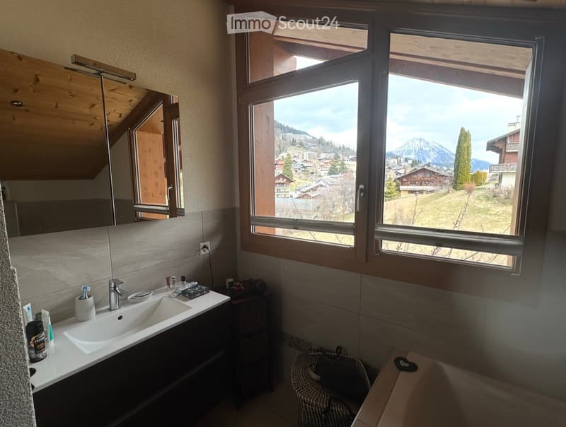 Bathroom with a sink, mirror, bathtub, and a window with a view of the mountains