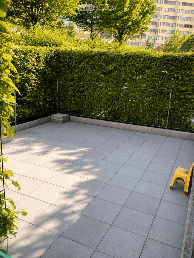 Balcony with tiled floor, greenery, and a yellow stool.