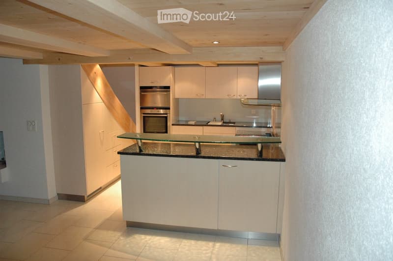Modern kitchen with white cabinets, stainless steel appliances, and a glass countertop island.