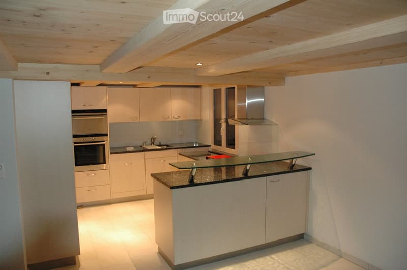 Modern kitchen with light-colored cabinets, stainless steel oven, glass island, and sleek countertops.