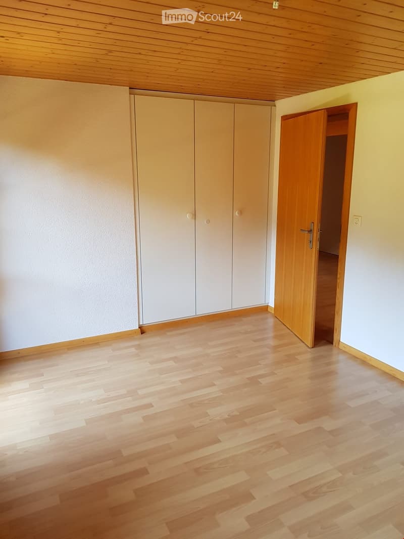 Empty room with light wooden flooring, white walls, and built-in closet with sliding doors.