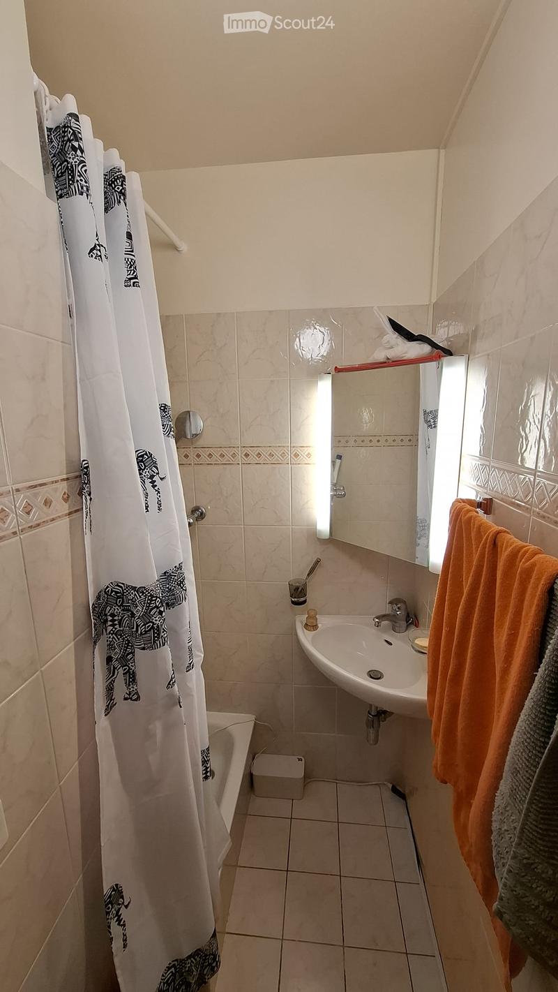 A small bathroom with a bathtub, a sink, a shower curtain, and a towel hanging on the side.