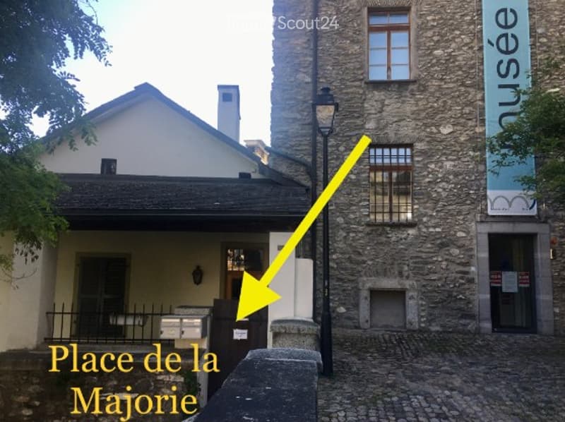 Exterior view of a historic stone building with a sign reading "musée" and a yellow arrow pointing to "Place de la Mairie".