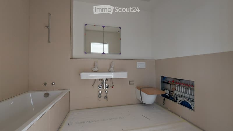 Bathroom with a bathtub, sink, mirror, and toilet. Exposed plumbing and unfinished walls are visible.