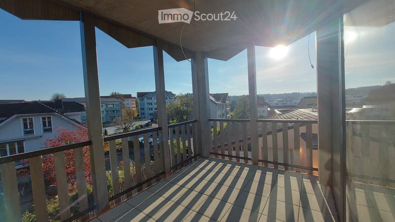 Balcony with a view of a residential area, featuring a metal railing and tiled floor.