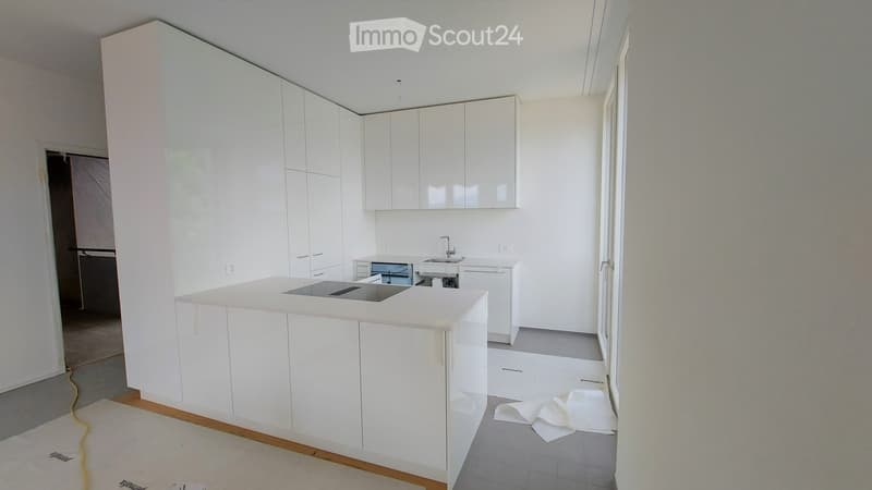 Modern kitchen with white cabinets, a central island, and a sink area. The space is clean and organized, with a neutral color palette.