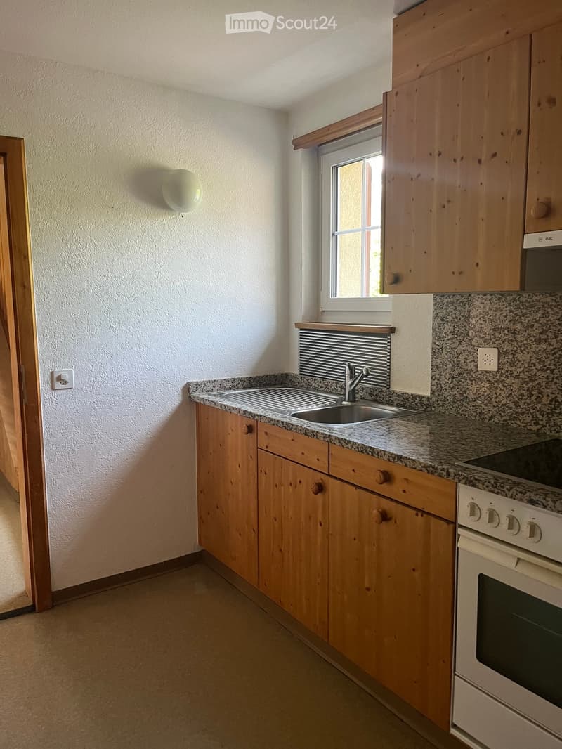 Compact kitchen with wooden cabinets, granite countertop, sink, faucet, and built-in oven.