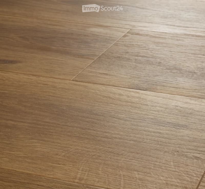 Close-up of a wooden floor with visible grain patterns and light brown tones.