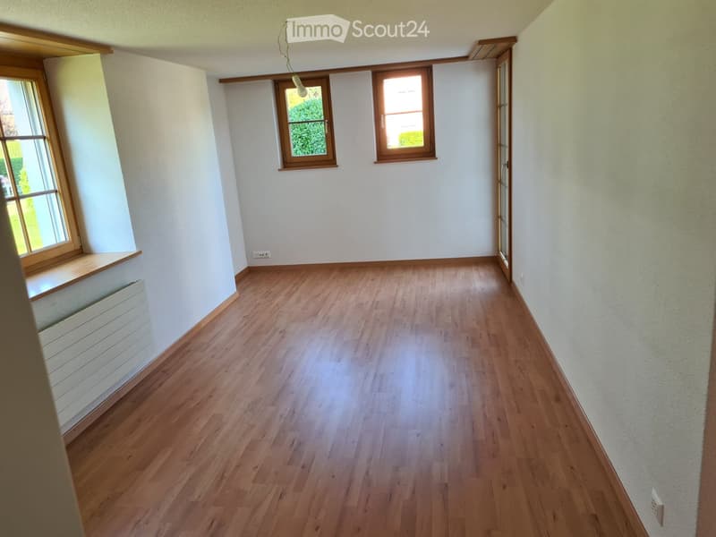 Empty room with wooden flooring, white walls, and multiple windows with wooden frames. No furniture or equipment present.