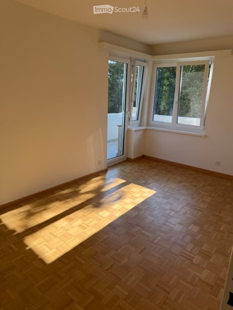 Empty room with wooden flooring and large windows allowing natural light. No furniture or equipment present.