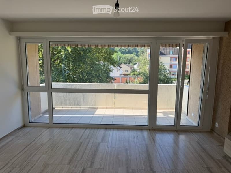 Empty room with large sliding glass doors leading to a balcony, wooden flooring, and natural light.