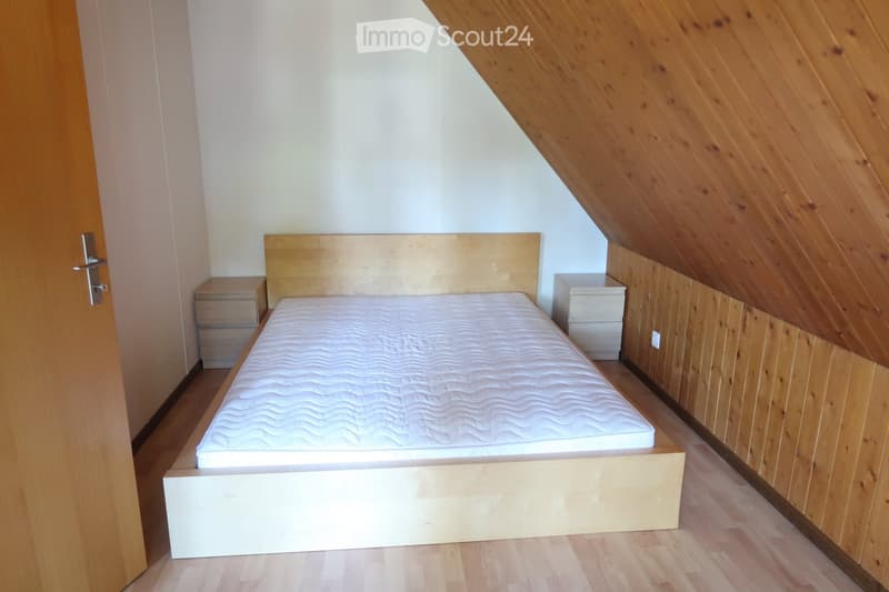 bedroom with wooden bed, two nightstands, wooden flooring, and sloped ceiling