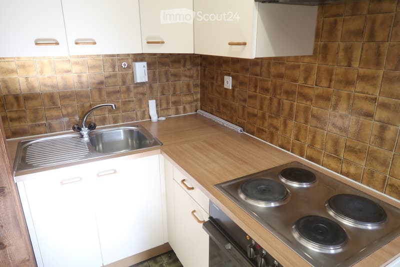white cabinets, wooden countertop, silver sink, stainless steel stove, tile walls