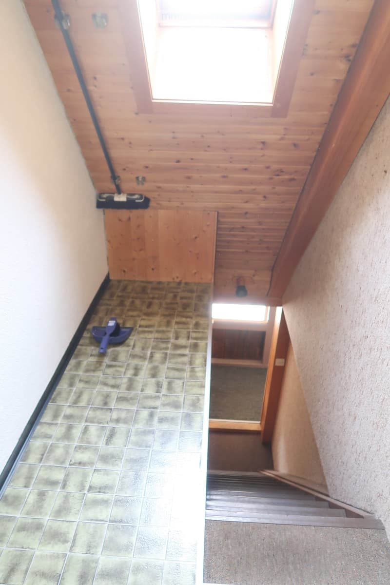 wooden ceiling, tiled floor, small window, stairs leading up, broom on the floor, wall with black line
