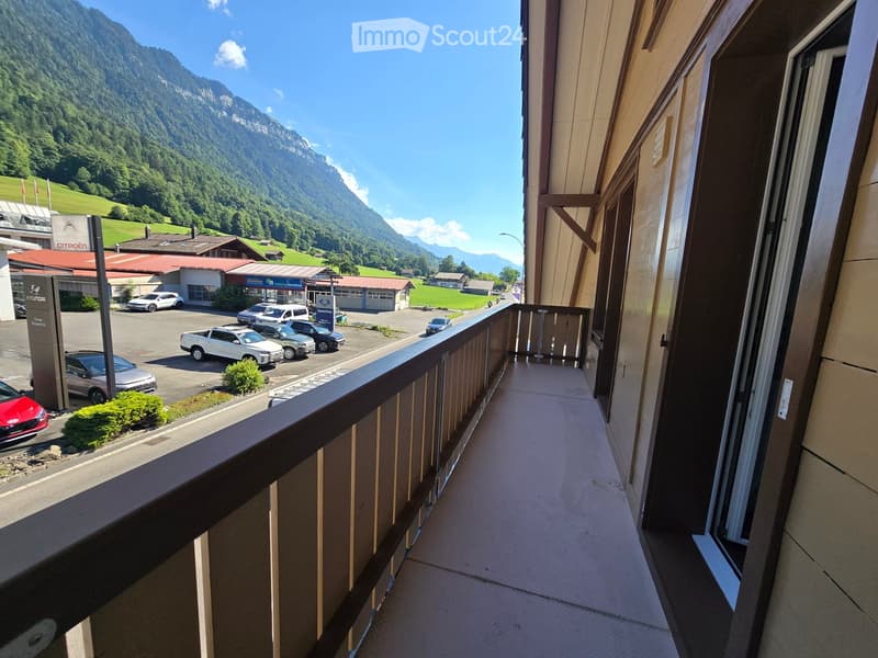 Balcony overlooking a parking lot and scenic mountain landscape with clear blue skies.