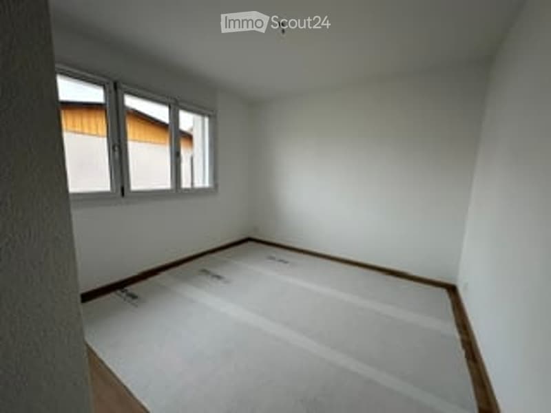 Empty room with white walls, wooden flooring, and three windows on one wall. No furniture or equipment present.