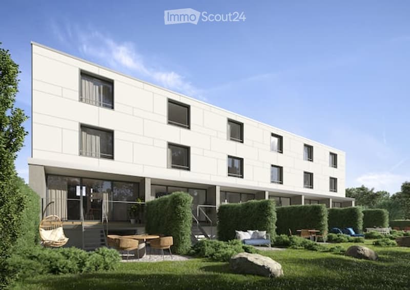 Modern multi-story building with white facade and large windows, surrounded by a well-maintained garden with seating areas and greenery.
