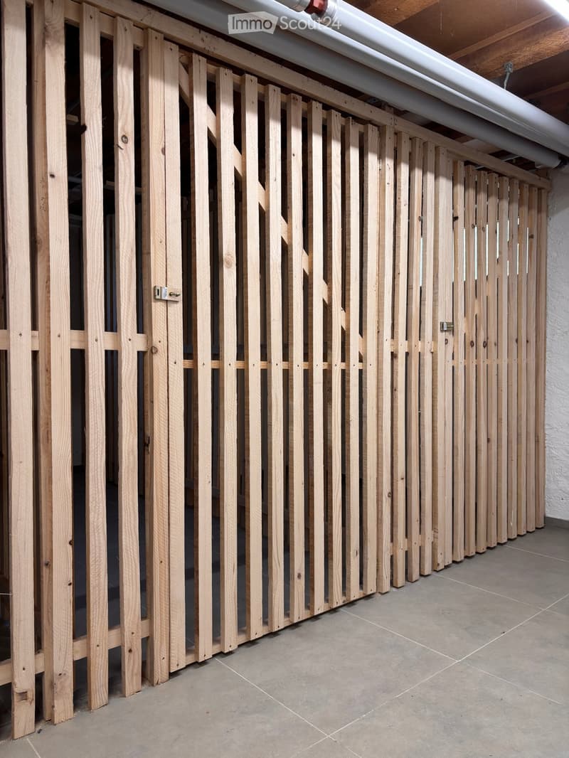 Empty room with wooden slatted partitions and tiled floor, no furniture or equipment.