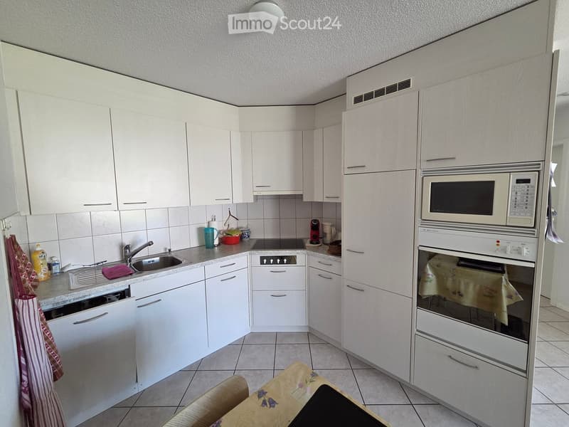 Modern kitchen with white cabinets, stainless steel appliances, and a tiled floor.