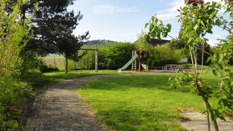 large grass field, brick path, slide, swing, picnic tables, trees