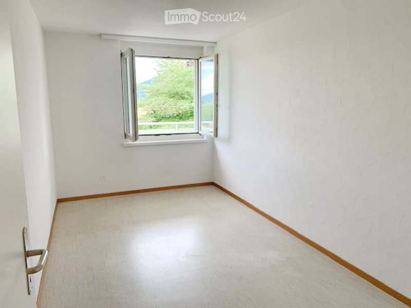 Empty room with white walls, white floor, window, door, and view of trees