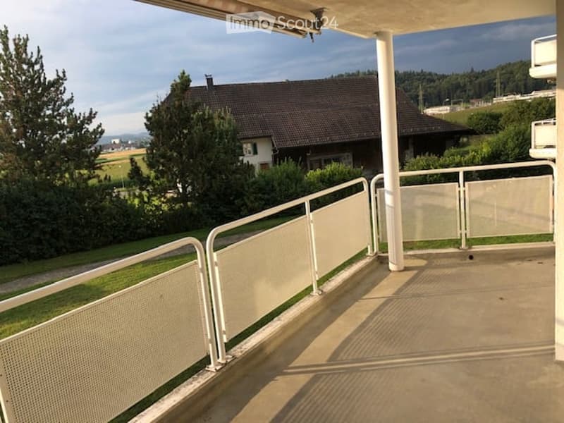 House, balcony, white railings, grassy lawn, tree, mountain view, sunny