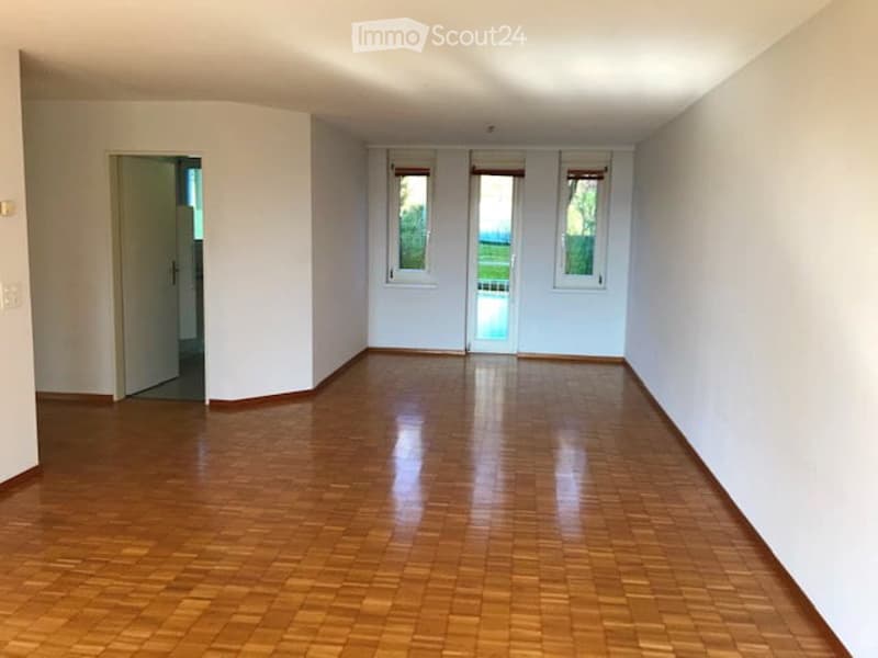 Empty room with wooden floors, white walls, and sliding glass doors leading to a balcony