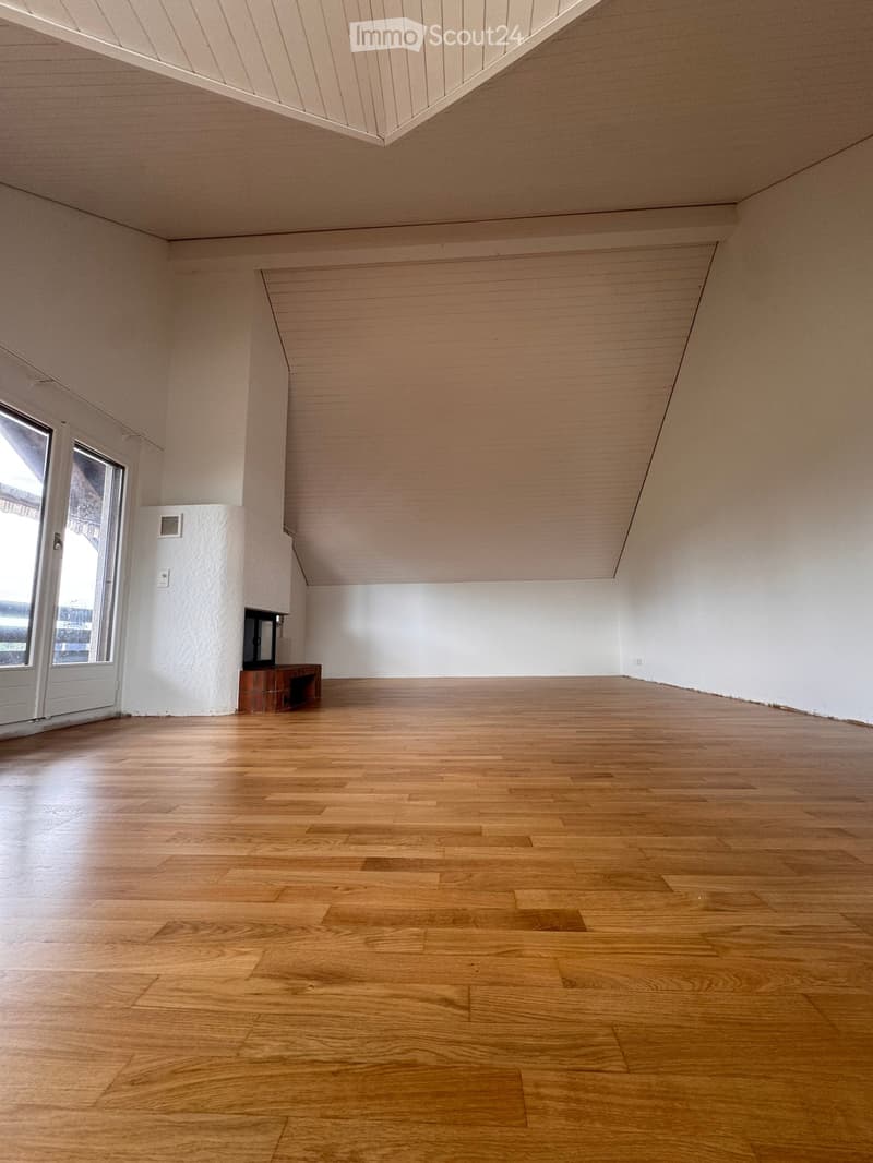 Empty room with wooden flooring, white walls, and a small built-in bench near a window.