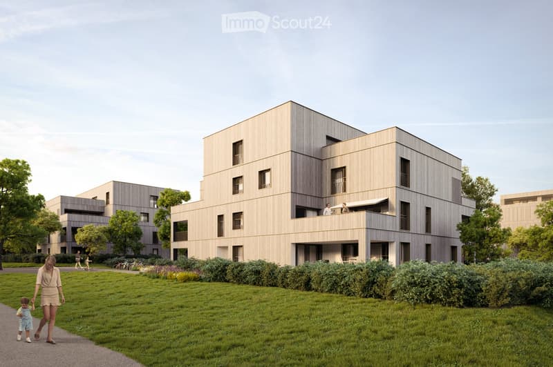 Modern multi-story building with a sleek, contemporary design, featuring large windows and a flat roof. The building is surrounded by a well-maintained lawn and trees, with a pathway leading to the entrance.