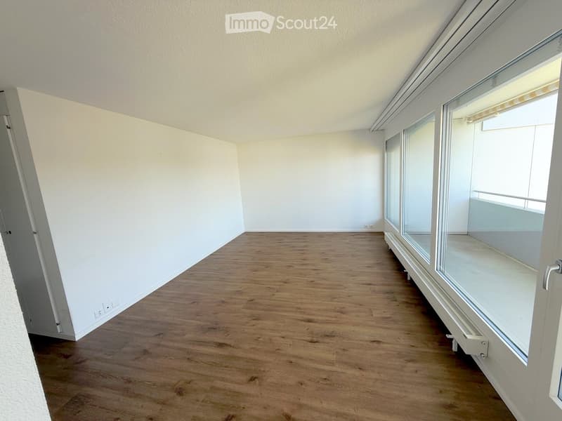 Empty room with wooden flooring, white walls, and large windows with blinds. No furniture or equipment present.