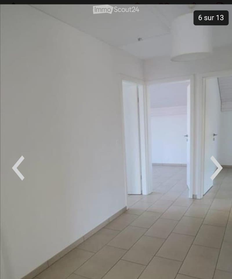 Empty hallway with white walls, tiled floor, and several doors leading to other rooms.