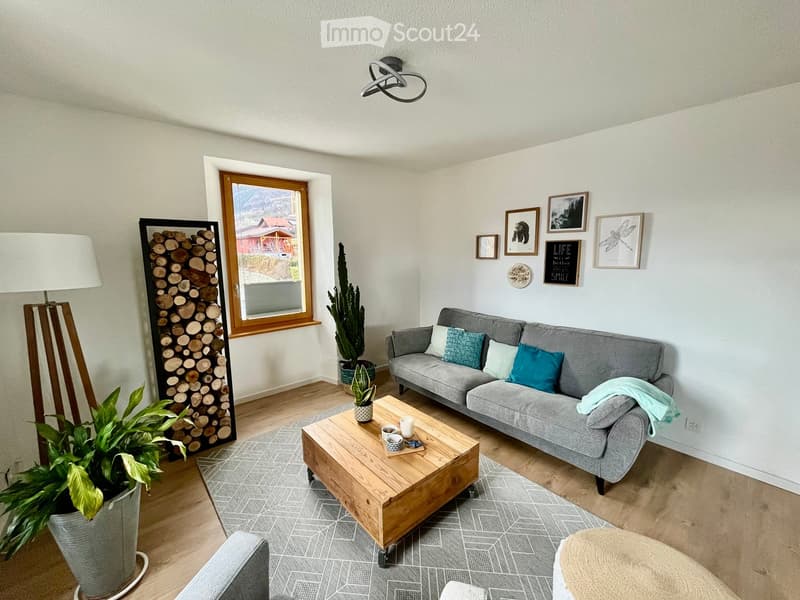 Modern living room with grey sofa, wooden coffee table, floor lamp, and decorative items on the wall.