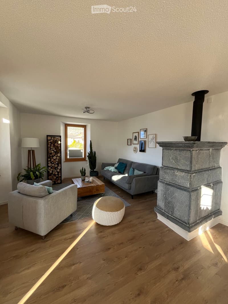Modern living room with wooden flooring, fireplace, grey sofa, coffee table, and decorative items.
