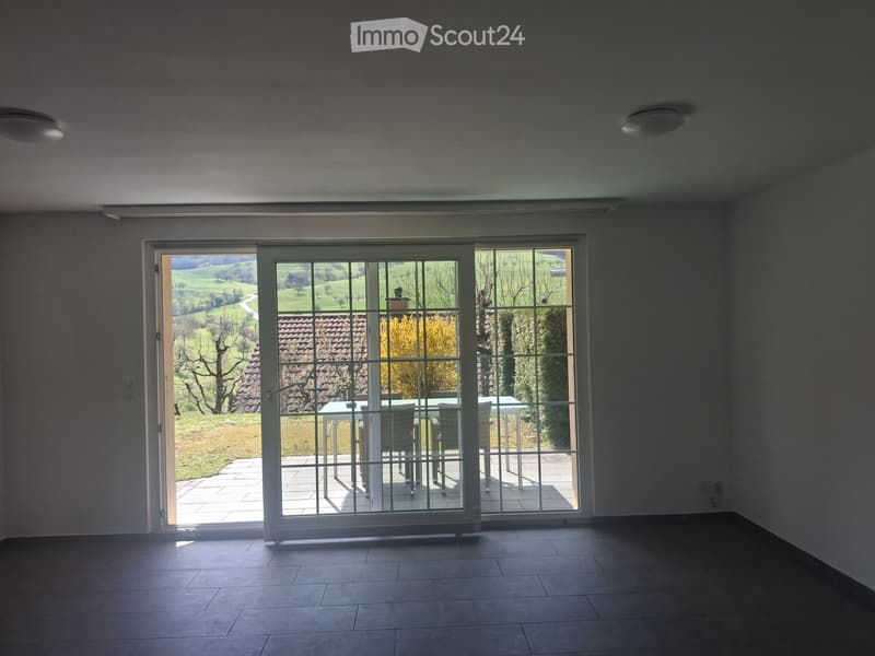 Empty room with large sliding glass doors leading to a patio, tiled floor, and visible outdoor landscape.