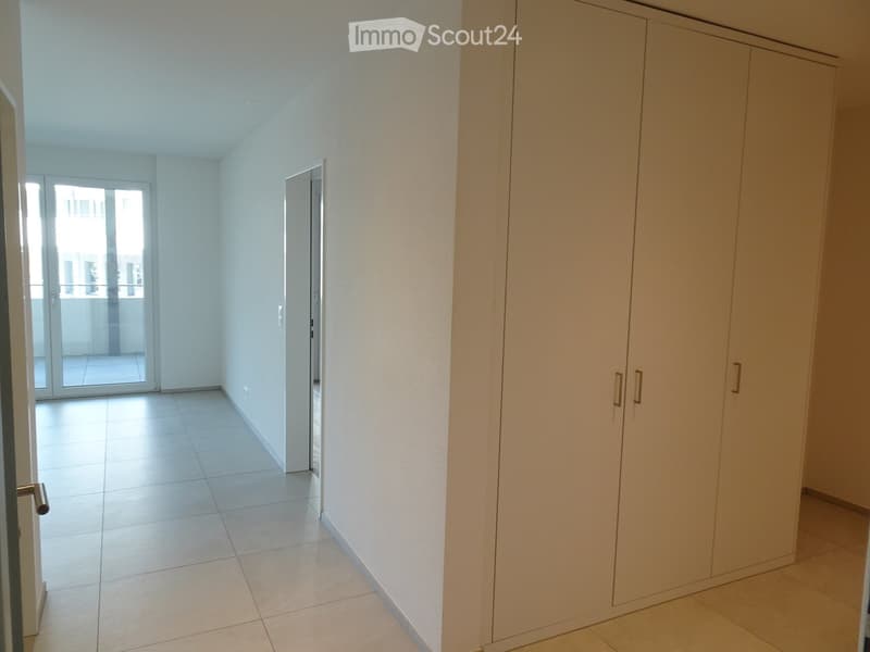 Empty room with tiled flooring, white walls, and a large built-in wardrobe. A sliding glass door leads to a balcony or outdoor area.