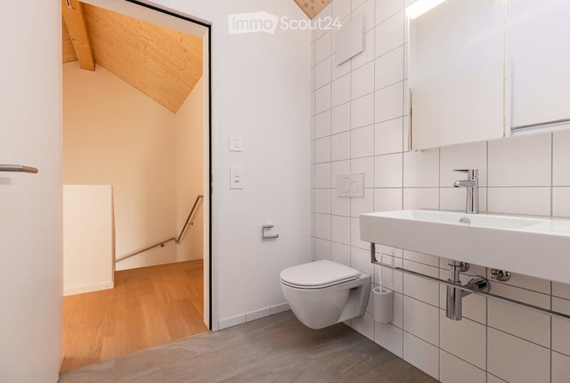 Clean modern bathroom with white walls and floors, a white sink, a toilet, a shower, and wooden floors