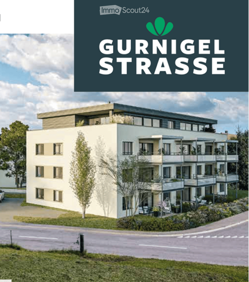 Modern multi-story residential building with balconies, large windows, and a contemporary design. The building features a clean, light-colored facade with a flat roof and is surrounded by greenery and a landscaped area.