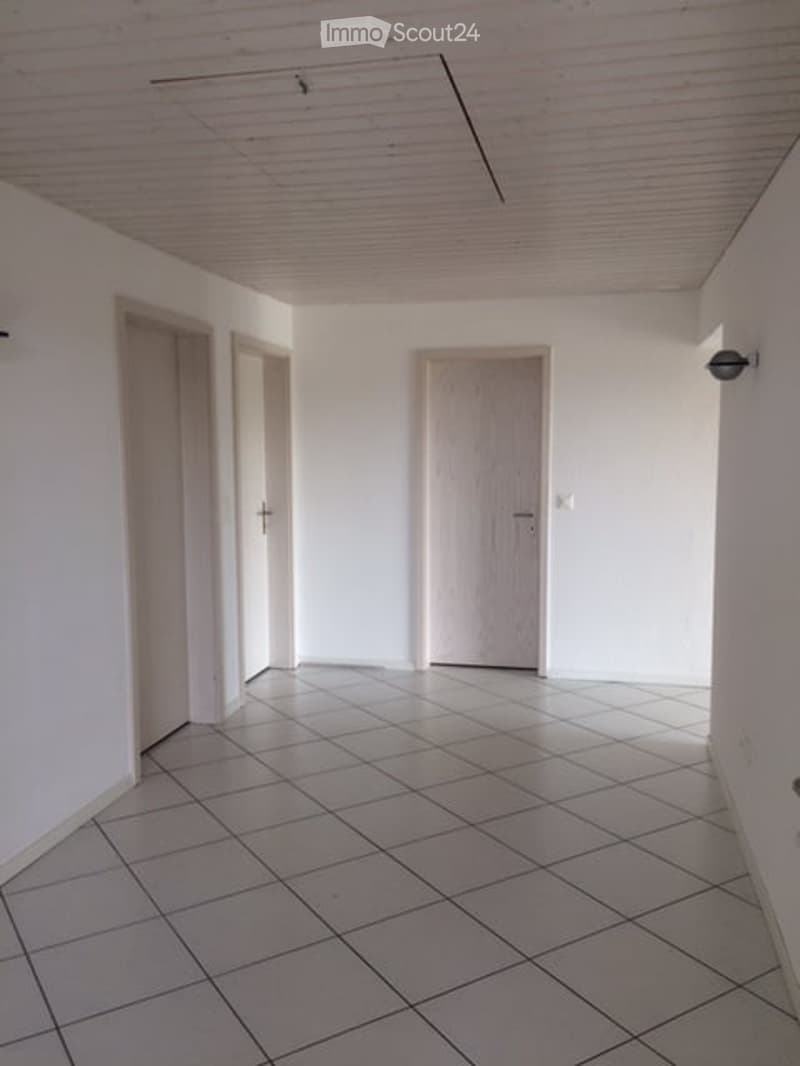 Empty hallway with white walls, tiled floor, and three doors.