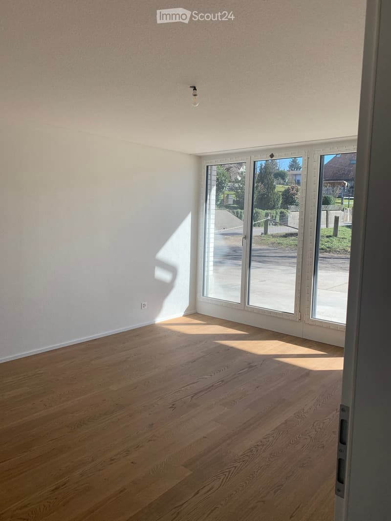 Empty room with wooden flooring and large sliding glass doors leading to an outdoor area.