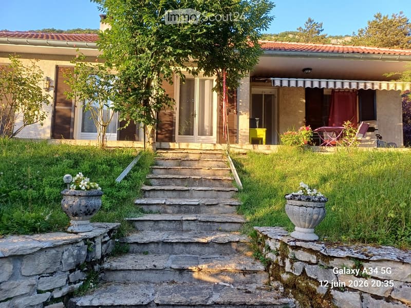 Two-story house with a tiled roof, large windows, and a covered porch area with outdoor furniture.