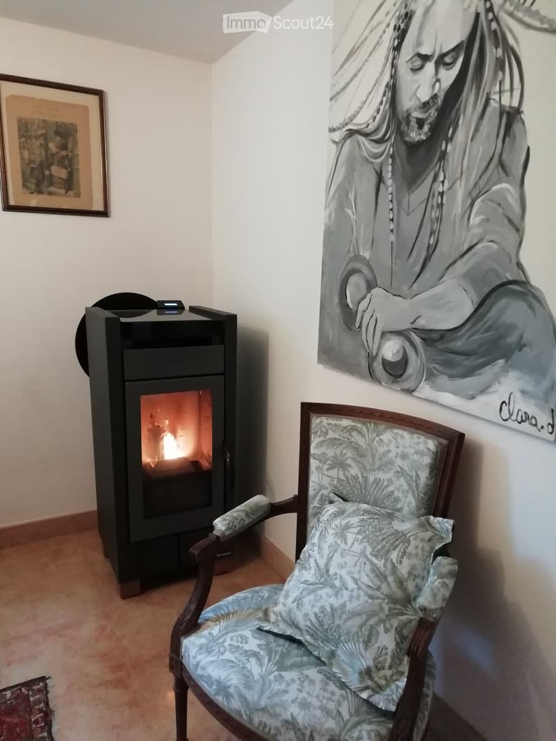 A cozy living space with a fireplace, a patterned armchair, and a large artwork on the wall.