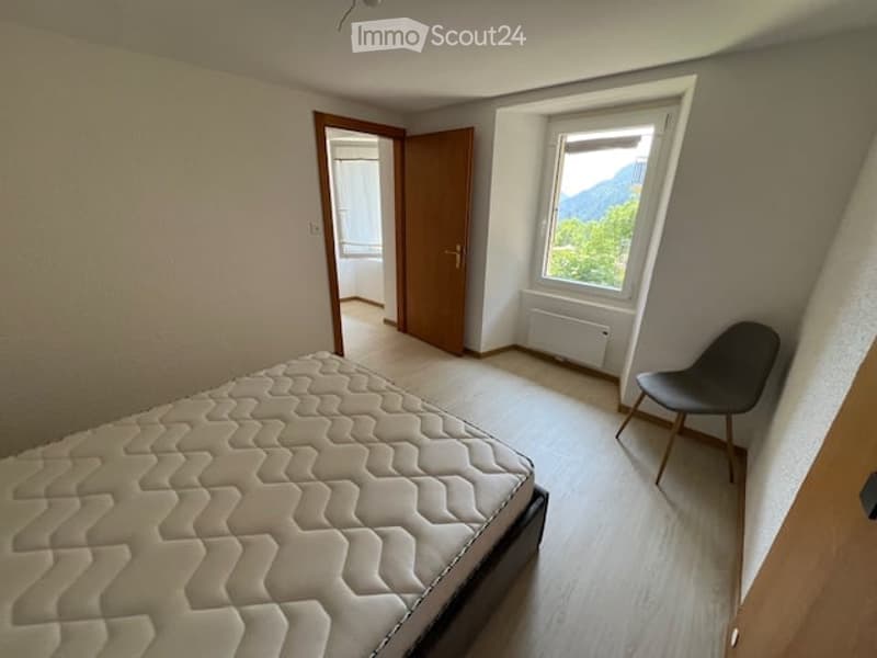 Bedroom with a large window offering a scenic mountain view, a single bed, and a modern chair.