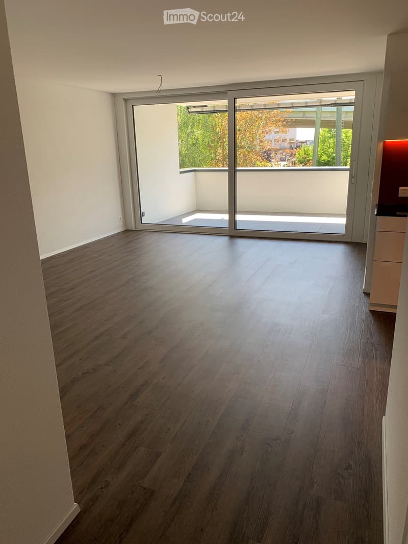 Empty room with wooden flooring and large sliding glass doors leading to a balcony or outdoor area.