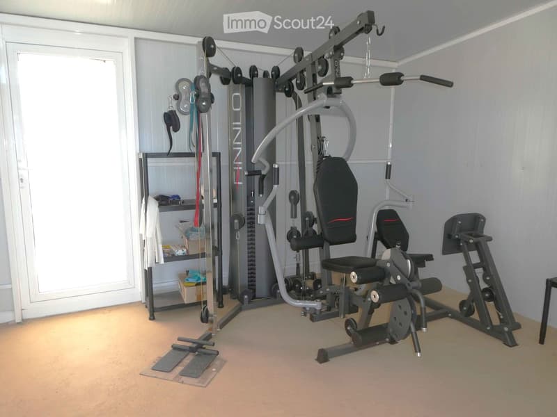 Well-equipped home gym with a multifunctional machine, bench, weight rack, and a towel hanging on the rack.