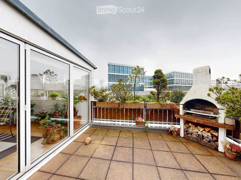 Terrace with tiled flooring, wooden railing, potted plants, and a brick barbecue. The terrace overlooks a cityscape with modern buildings and trees.