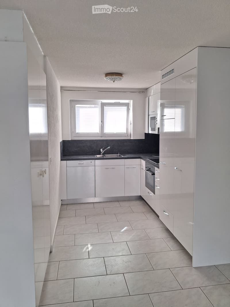 Modern kitchen with white cabinets, tiled floor, and built-in appliances including a sink, oven, microwave, and dishwasher.